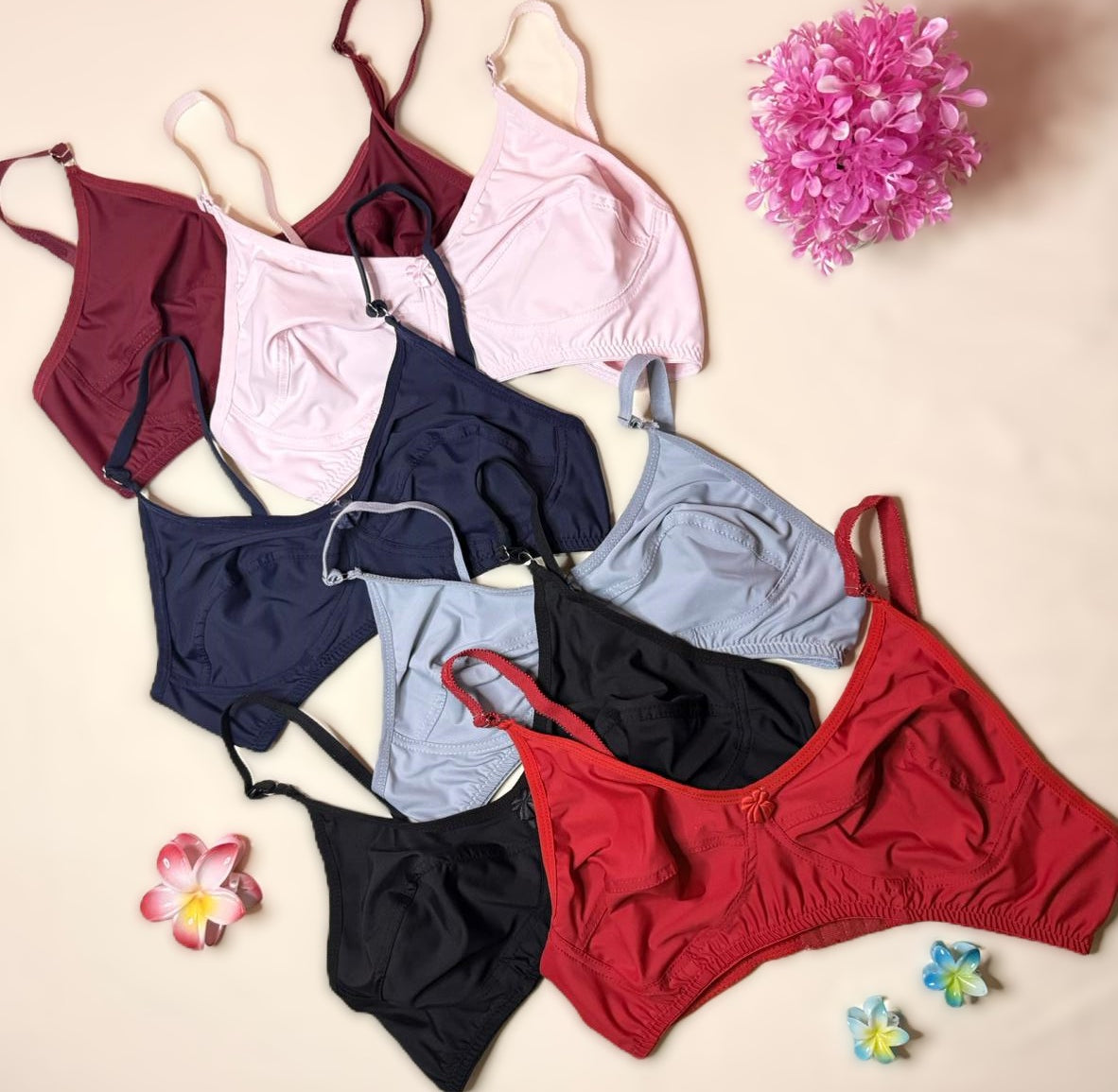 Collection of colorful bikini sets on a beige background with decorative flowers.